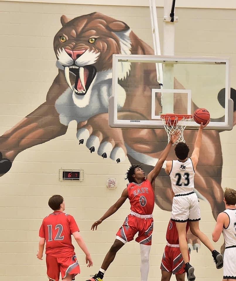 SaberCat player attacking the basket beneath the Fossil Ridge mural